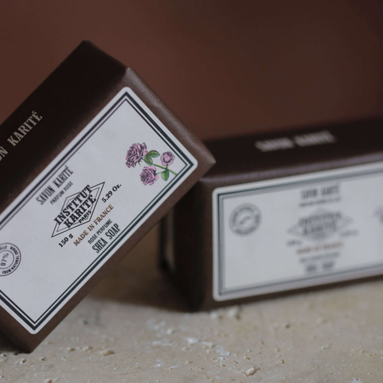 Two 150g Rose Shea Soap boxes by Institut Karité Paris on a travertine surface, front label in focus