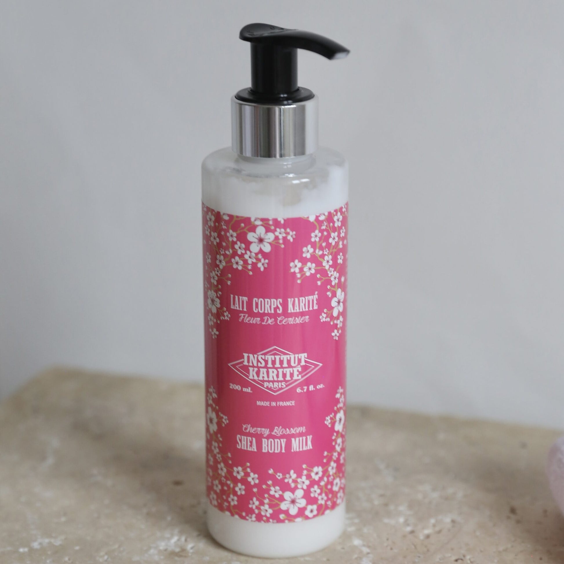 200mL Cherry Blossom Shea Body Milk by Institut Karité Paris on a travertine surface