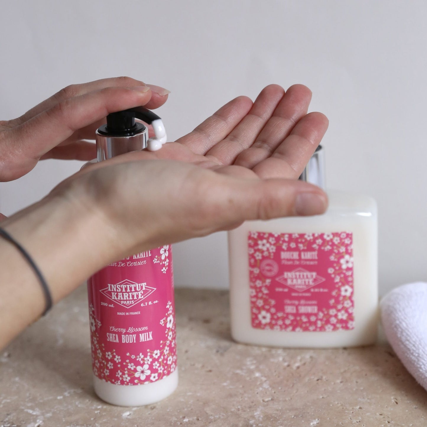Cherry Blossom Shea Body Milk by Institut Karité Paris being dispensed into an open palm