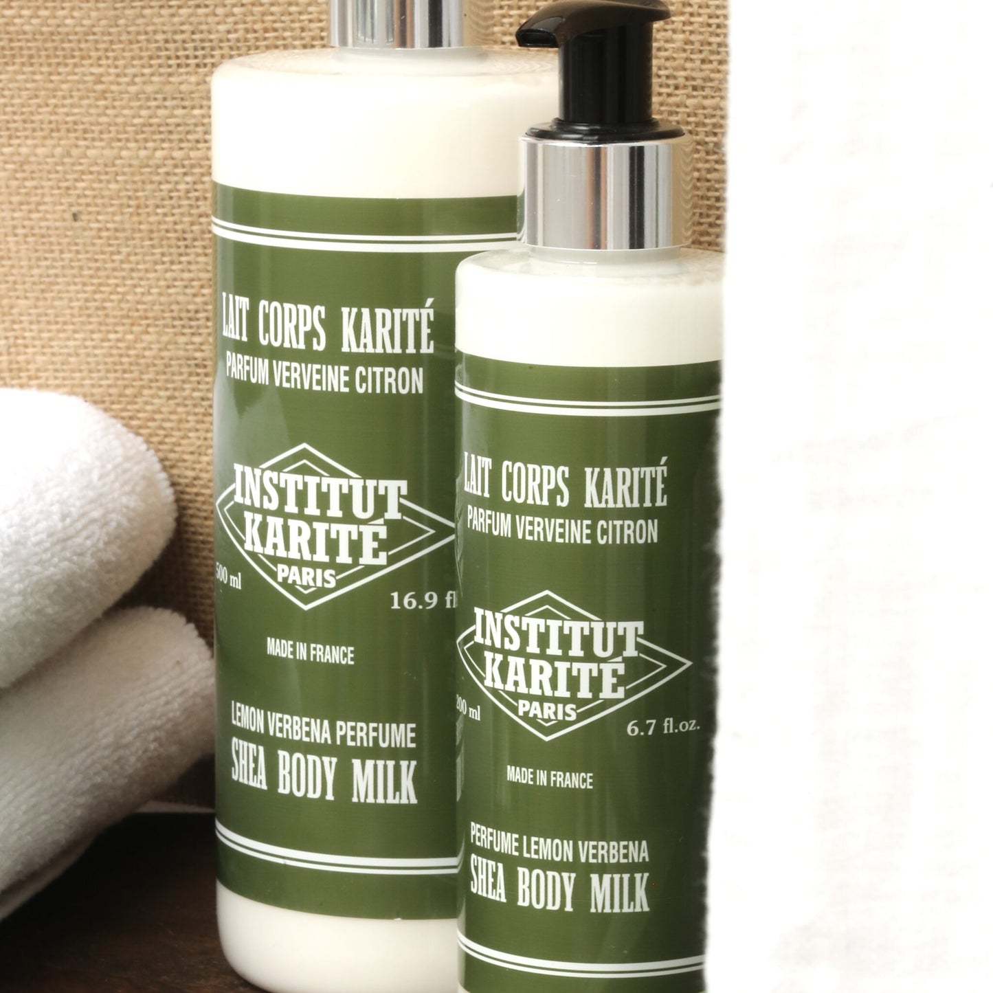 500mL and 200mL Lemon Verbena Shea Body Milk by Institut Karité Paris on burlap with folded white towels