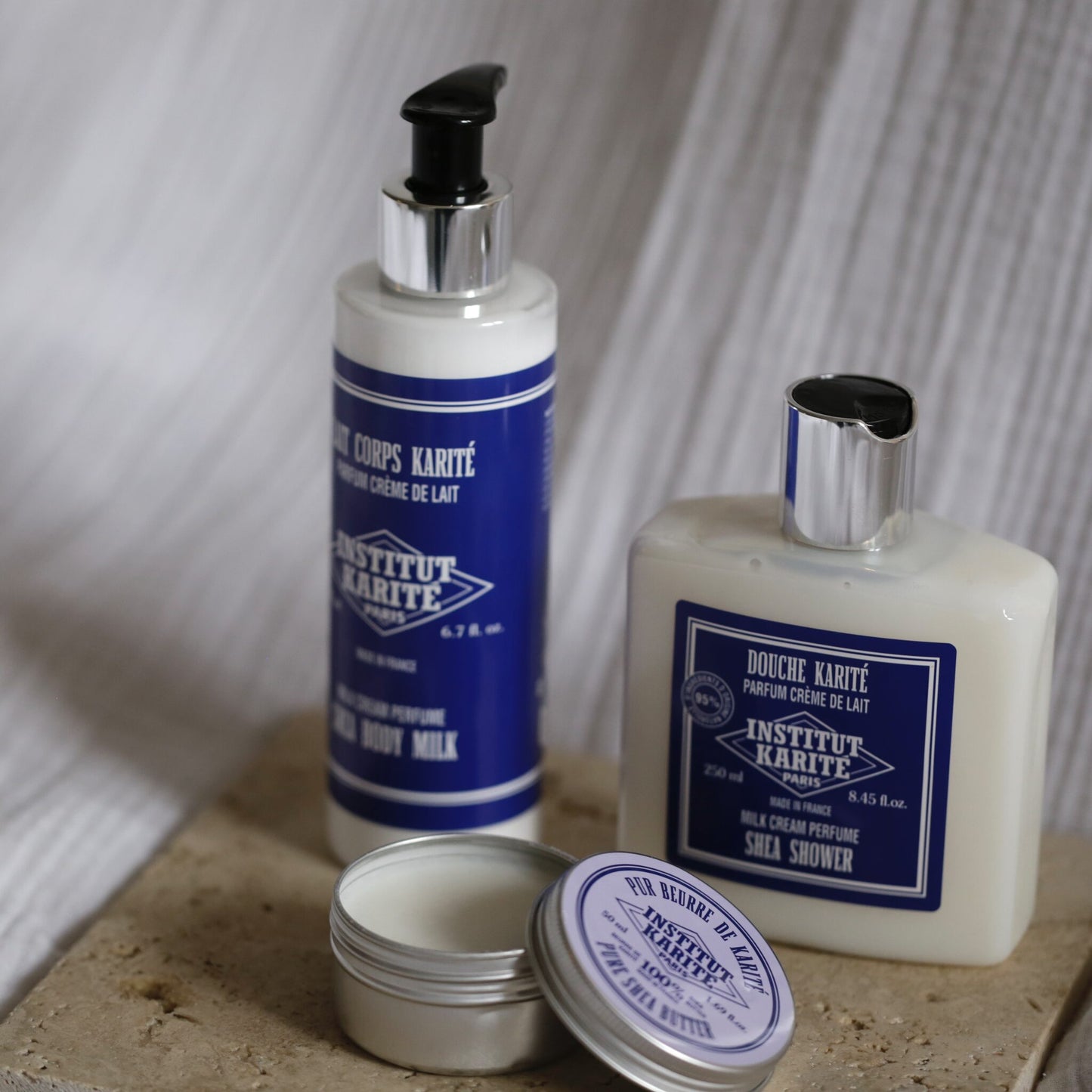 Milk Cream Shea Body Milk and Shea Shower gel by Institut Karité Paris beside an open tin of pure shea butter