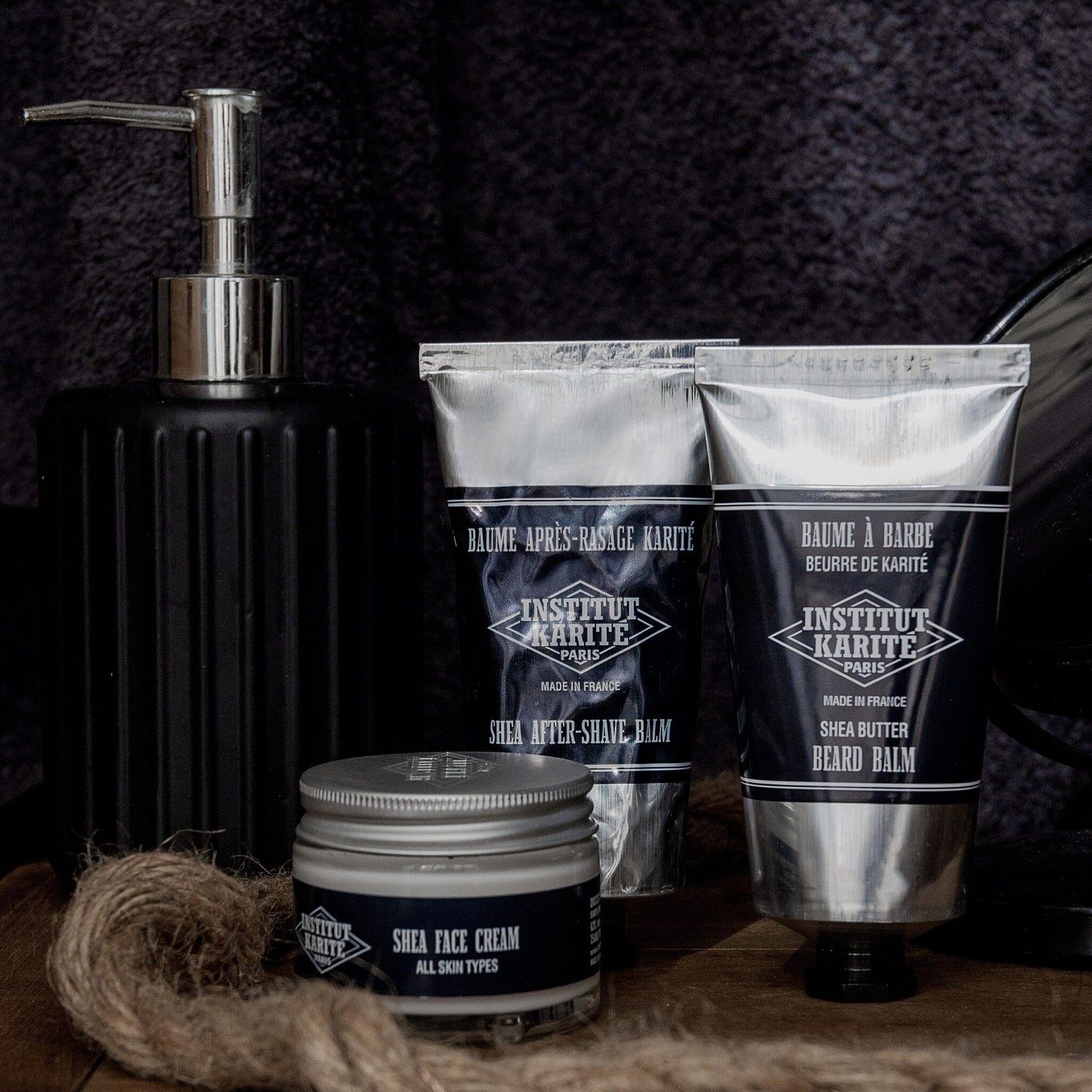 Shea After Shave Balm tube with Shea Butter Beard Balm and a Shea Face Cream jar on dark wood
