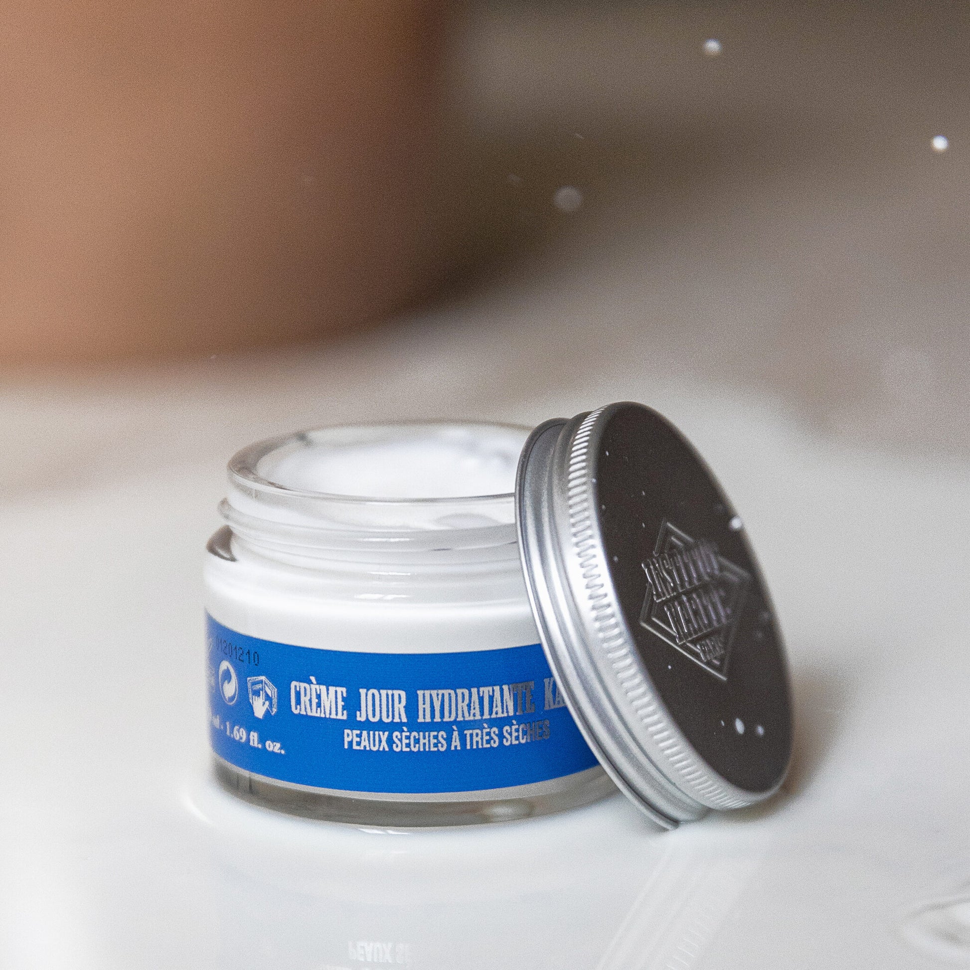 Open jar of Shea Moisturising Day Cream showing its texture with the lid resting beside it