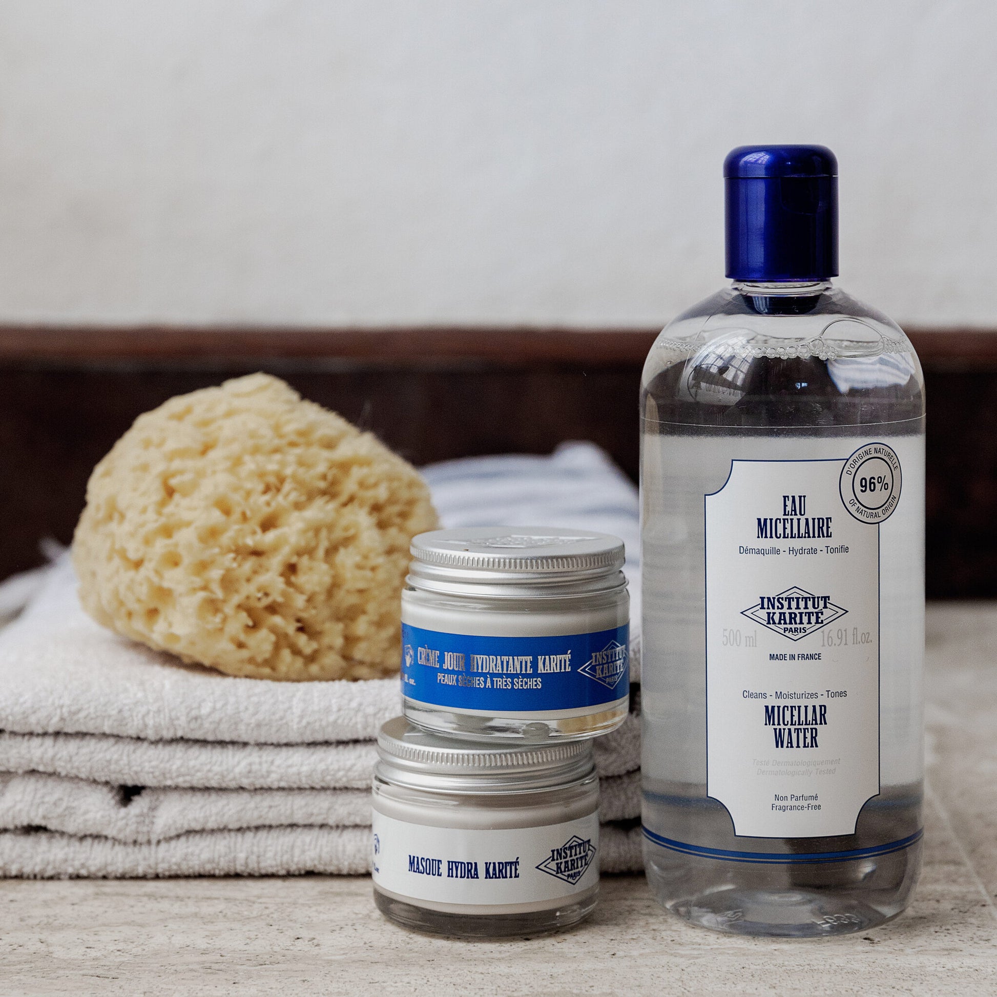 Shea Moisturising Day Cream and Hydra Mask jars beside a Micellar Water bottle with a natural sponge and folded towels