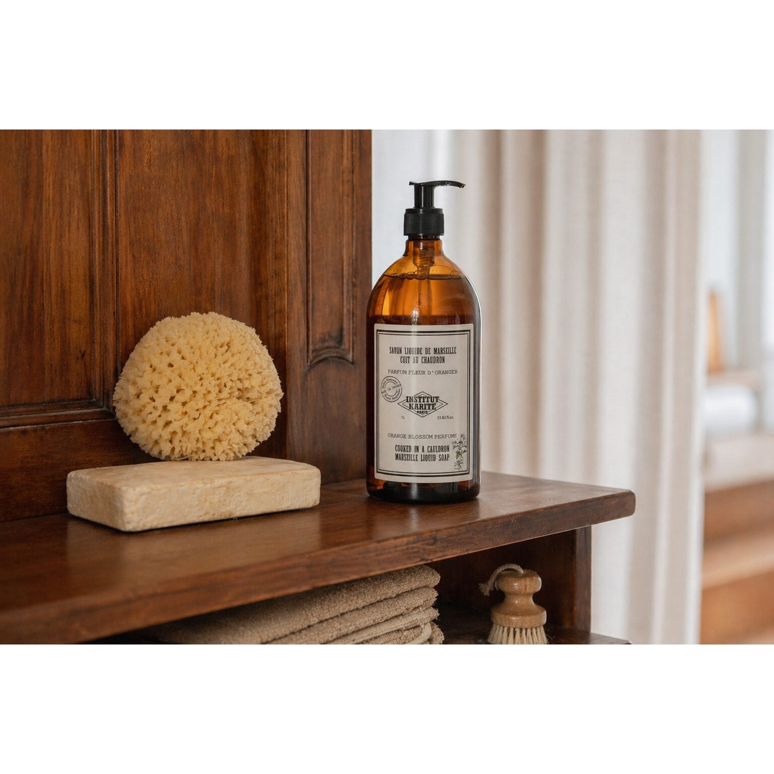 Orange Blossom Marseille Liquid Soap on a wooden shelf with a natural sponge and soap bar