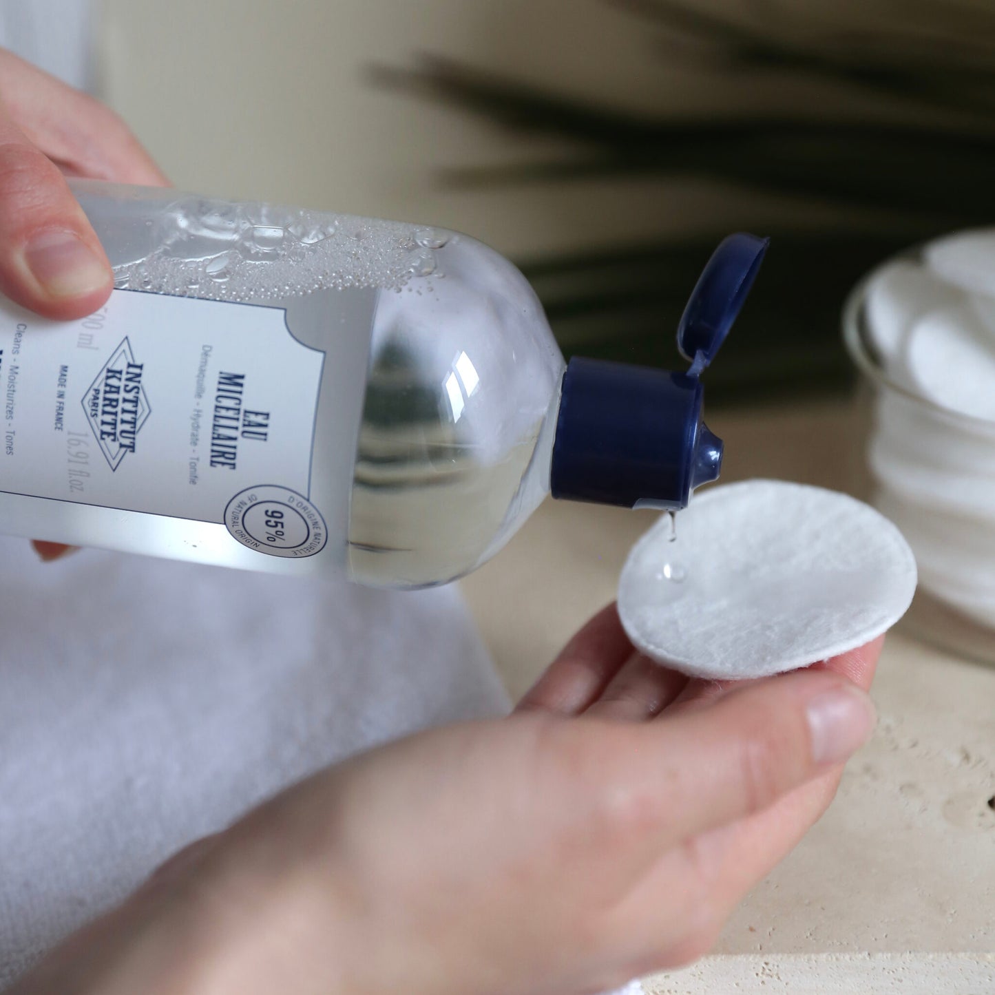 Micellar Water being poured onto a cotton pad held in the hand