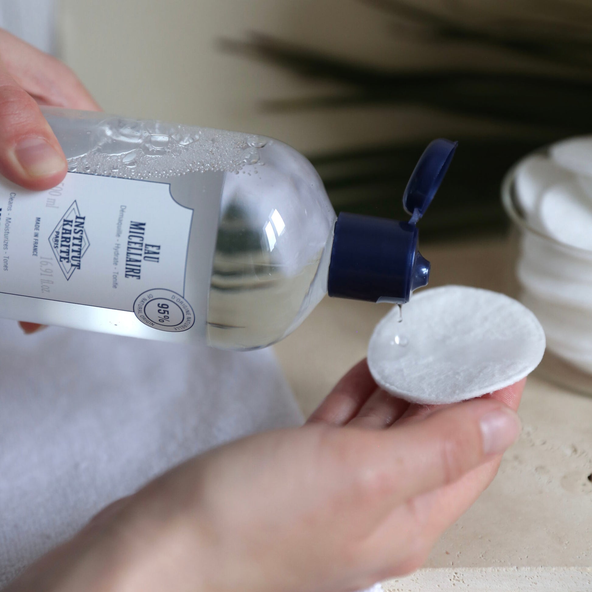 Micellar Water being poured onto a cotton pad held in the hand