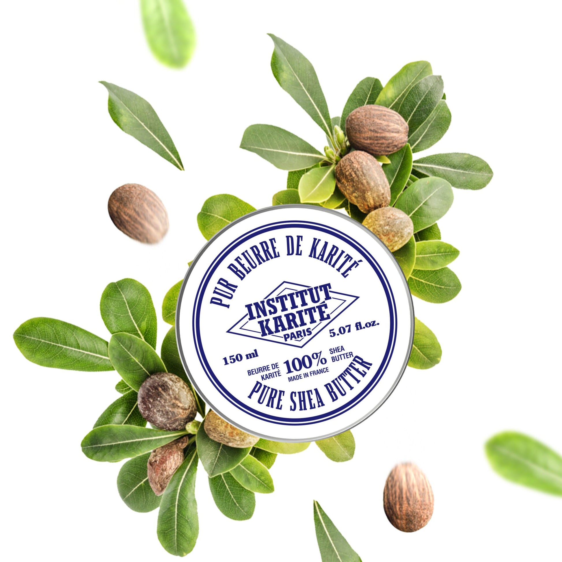 150 ml tin of Institut Karité Paris Pure Shea Butter surrounded by whole shea nuts and green leaves on a white background