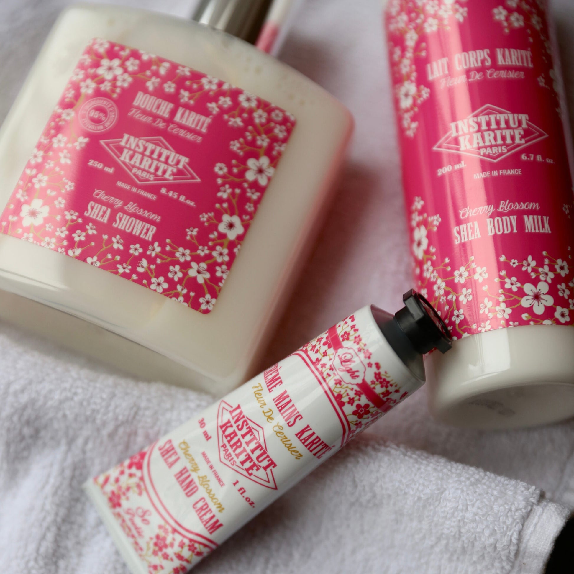 Cherry Blossom Shea Shower, Body Milk and Hand Cream resting on a white towel