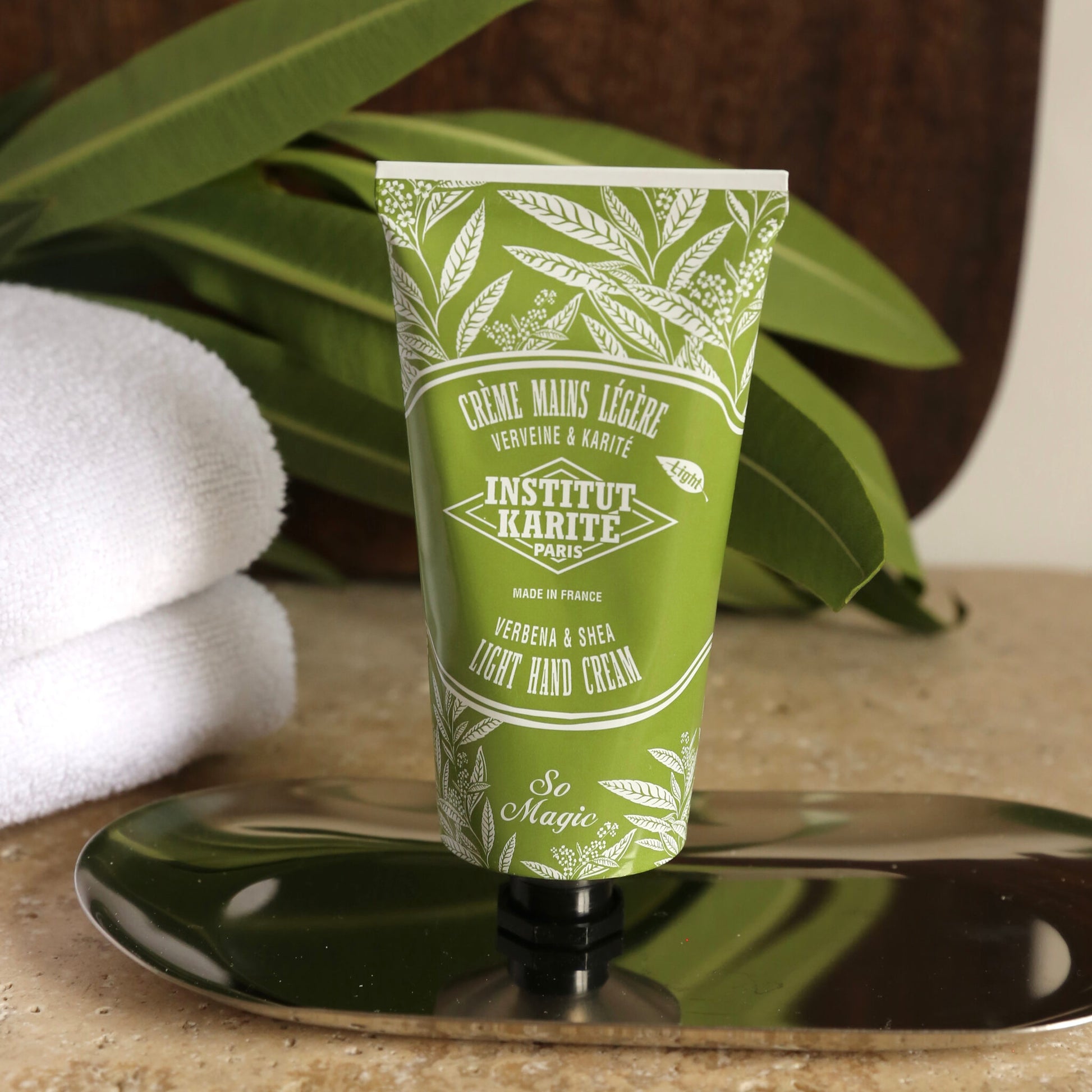 Light Hand Cream Verbena and Shea tube on a tray with folded towels and green foliage